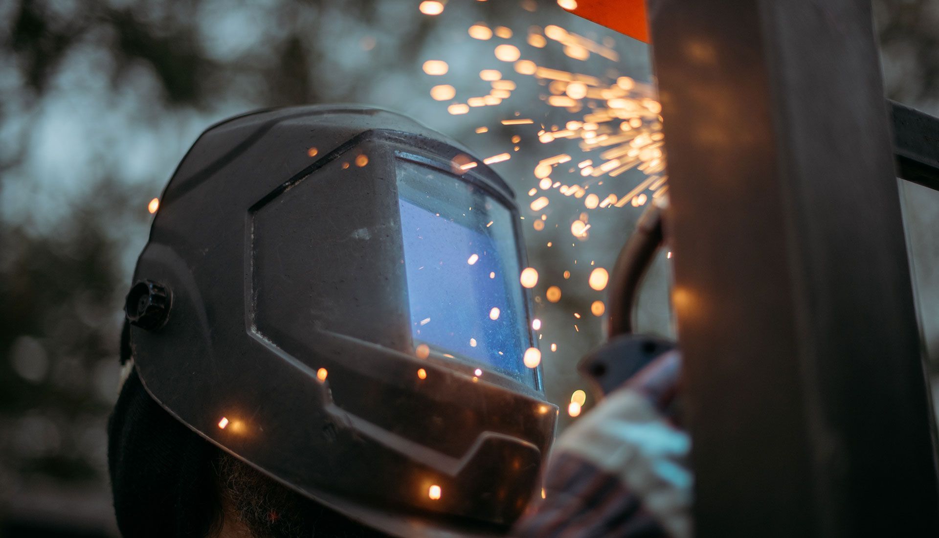 Welder wearing a helmet, sparks flying.
