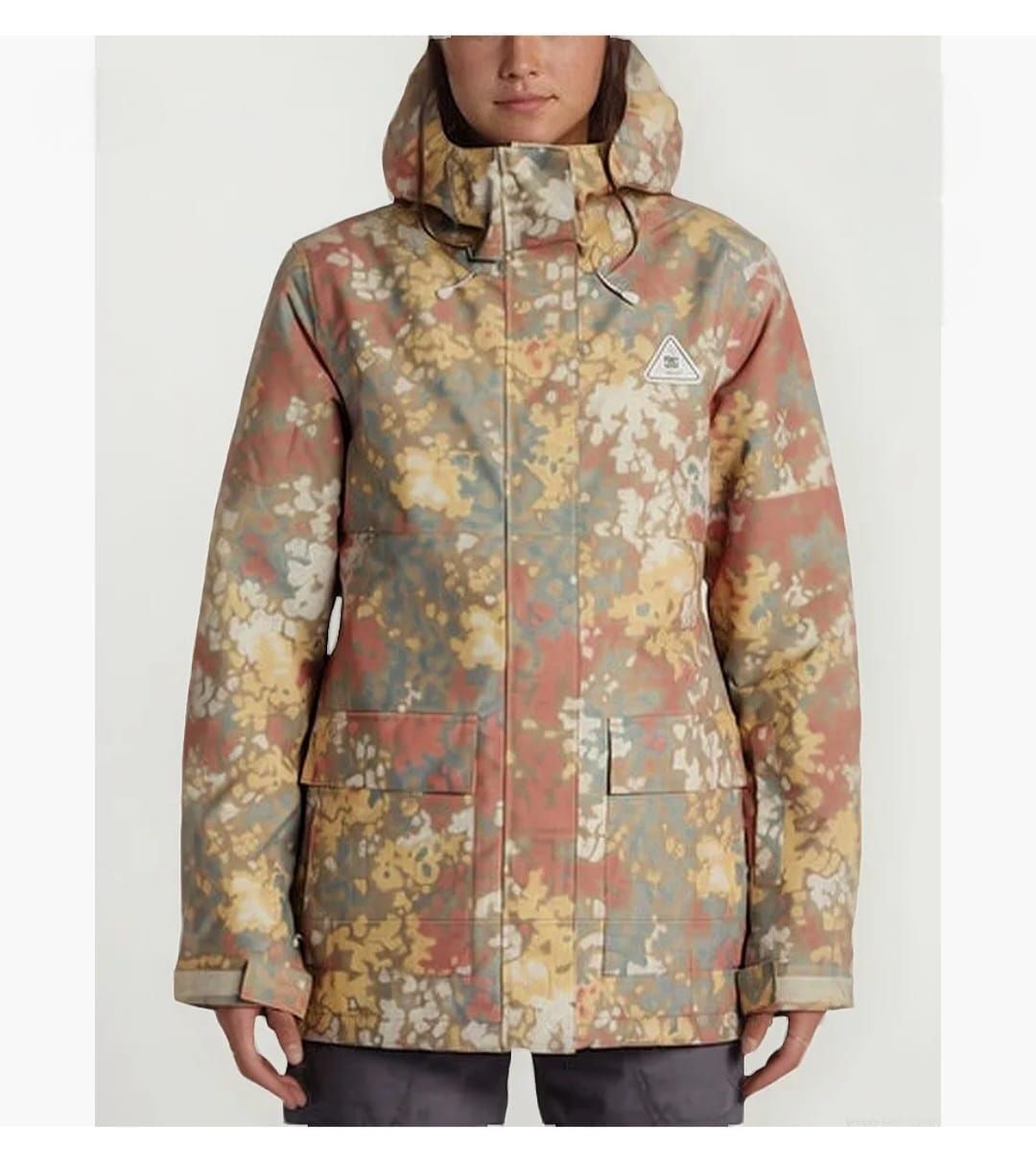 Mujer que lleva una chaqueta de camuflaje color canela, amarillo y rojo con capucha.