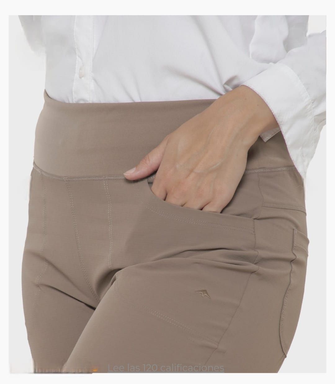 Mujer con pantalones color beige, mano en el bolsillo y camisa blanca.