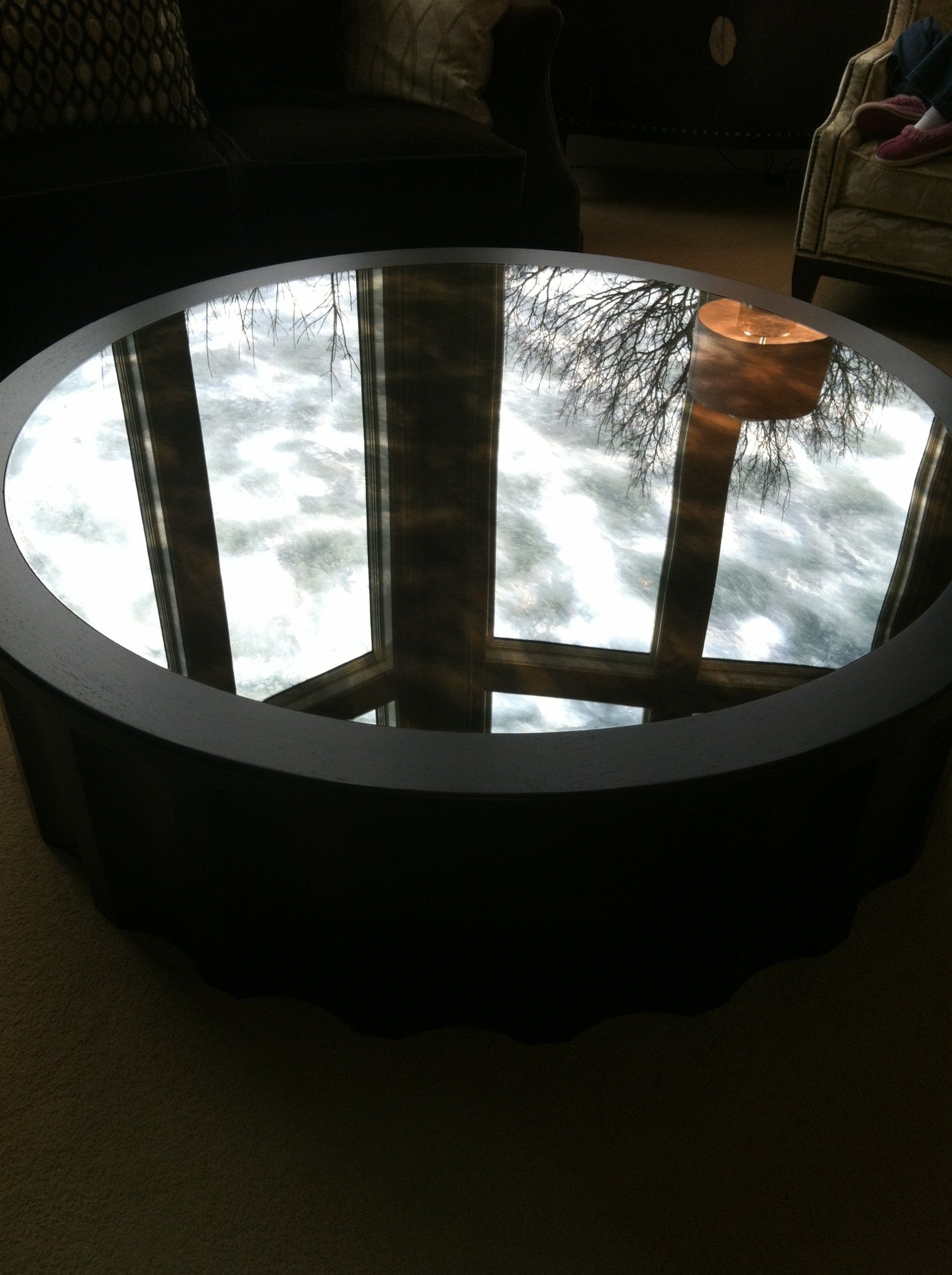 A round coffee table with a mirrored top in a living room
