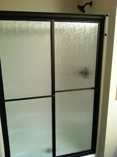 A bathroom with a sliding glass shower door and a shower head.