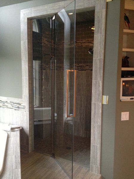 A bathroom with a walk in shower with a glass door