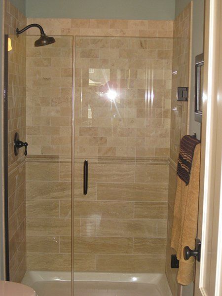 A bathroom with a walk in shower with a glass door