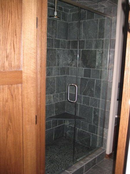 A bathroom with a walk in shower with a glass door