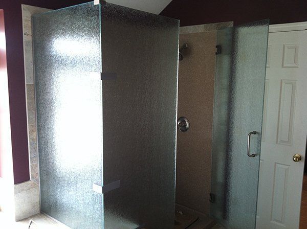 A bathroom with a shower stall and a window.
