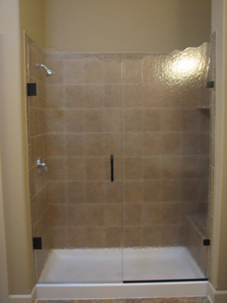 A bathroom with a walk in shower with a glass door.