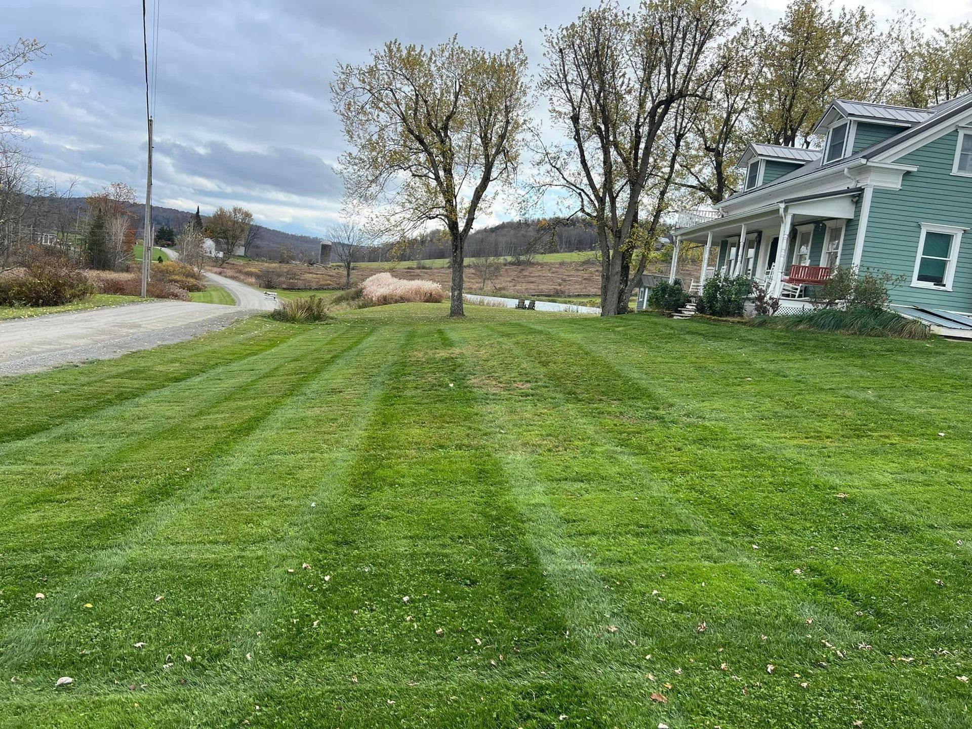 Freshly mowed green lawn beside a blue house under a cloudy sky