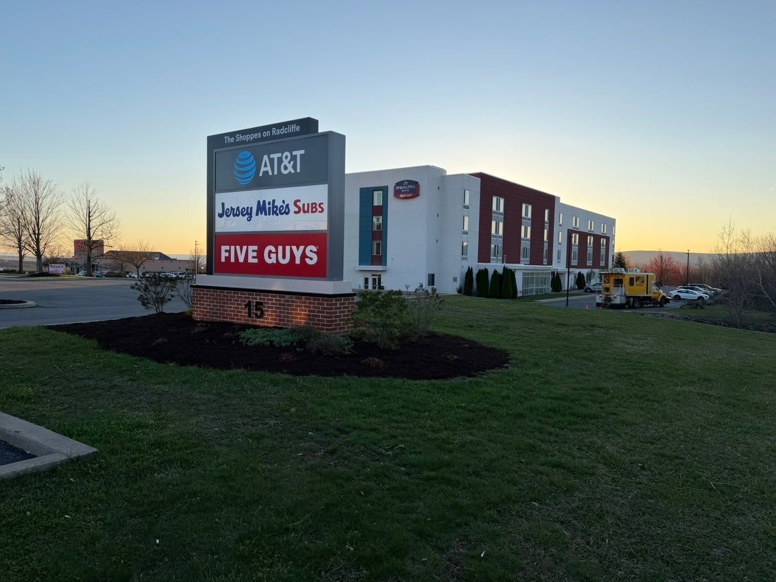 AT&T and Five Guys storefront at dusk with a roadside sign in front