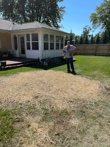A man is standing in the grass in front of a house.