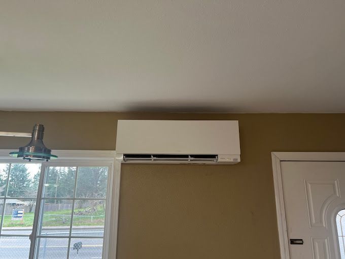 A room with a window and a white air conditioner on the wall.