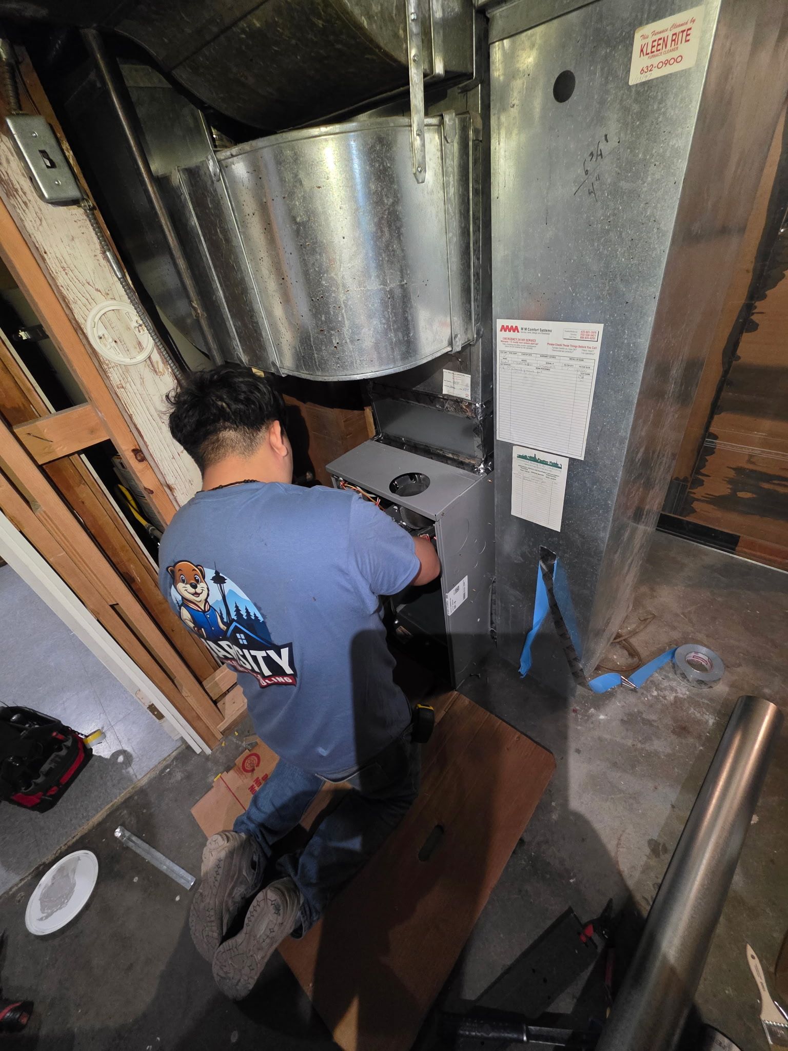 Varsity Heating & Cooling technician installing a new gas furnace in a Tacoma basement, ensuring proper wiring and airflow setup
