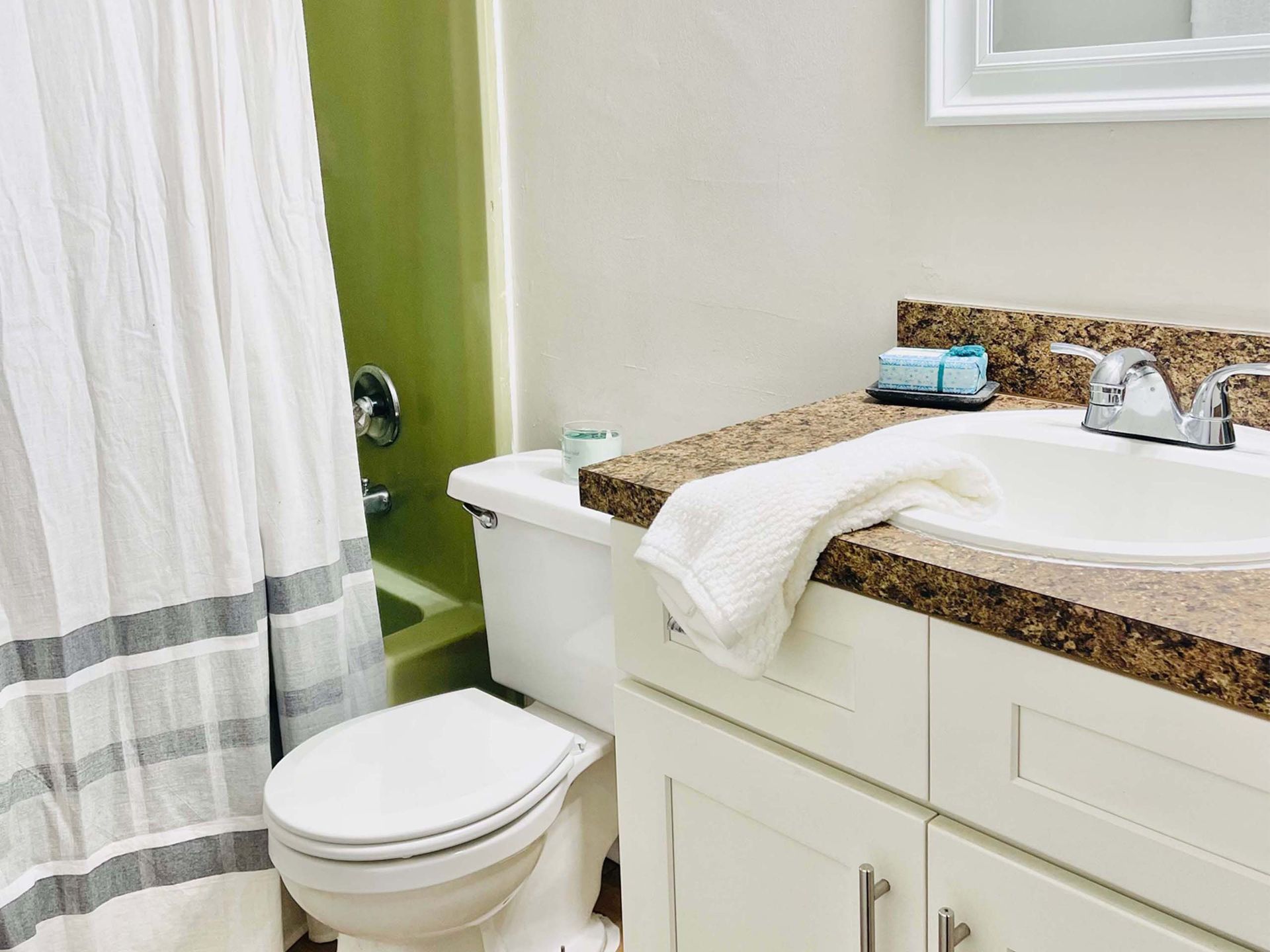 A bathroom with a toilet , sink , and shower curtain.
