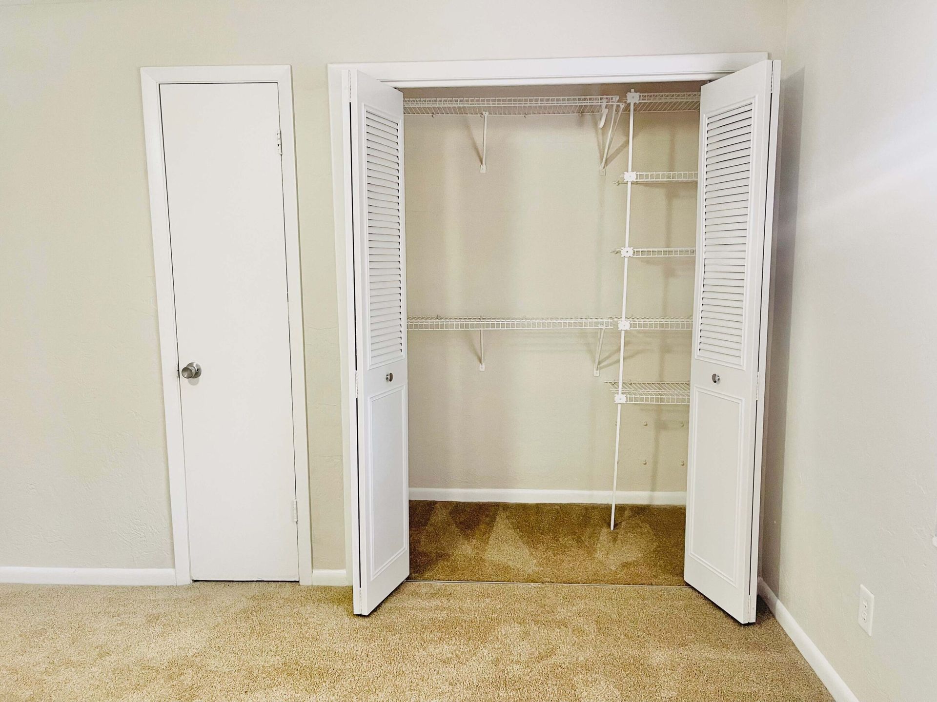 An empty bedroom with a walk in closet with the doors open.