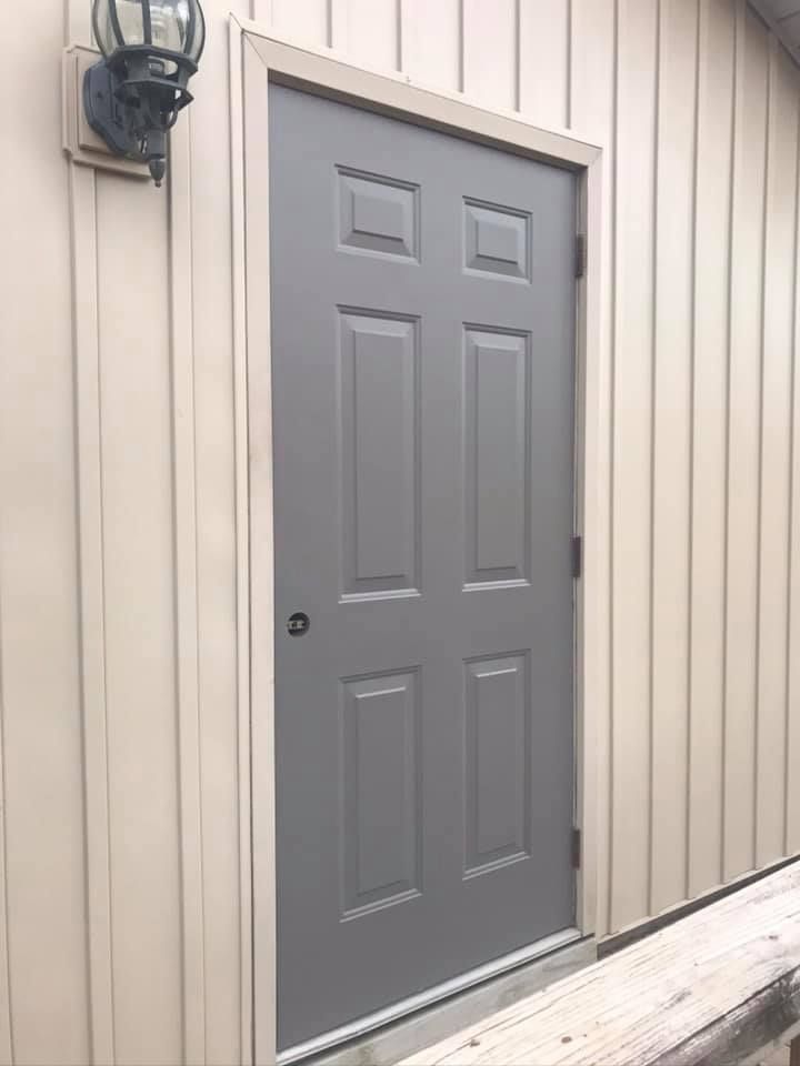 Gray six-panel door in a tan building with light-colored trim.