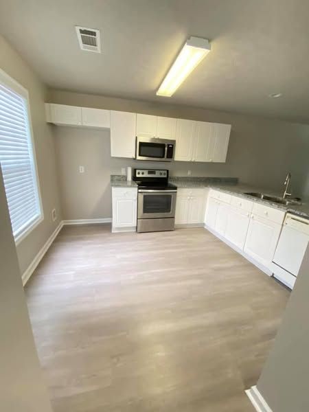 Kitchen with white cabinets, stainless steel appliances, and light-colored flooring.