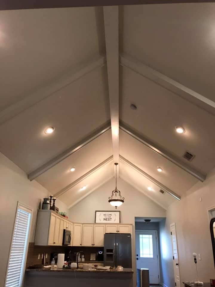 Vaulted ceiling in a kitchen with recessed lights, a hanging light, and white cabinets.