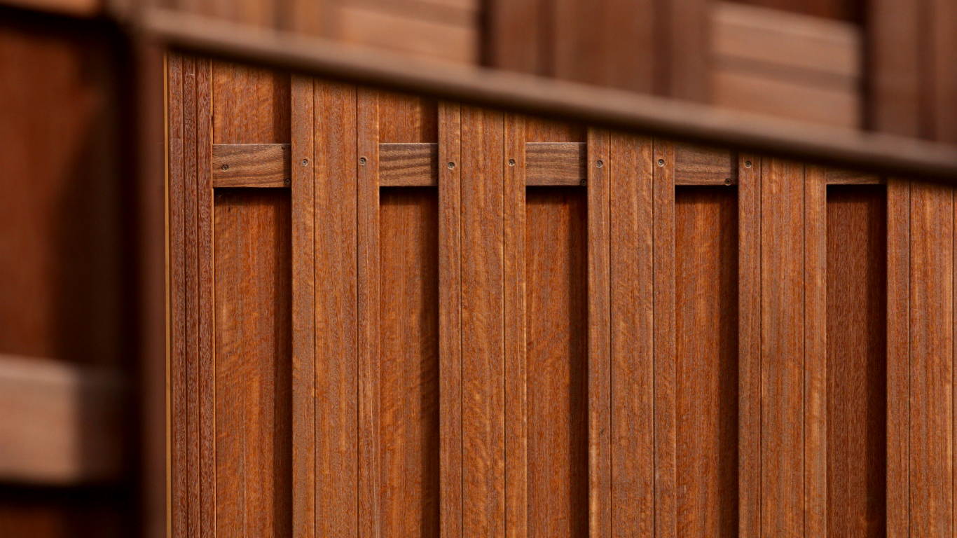 Brown wooden fence with vertical planks and horizontal joiners.