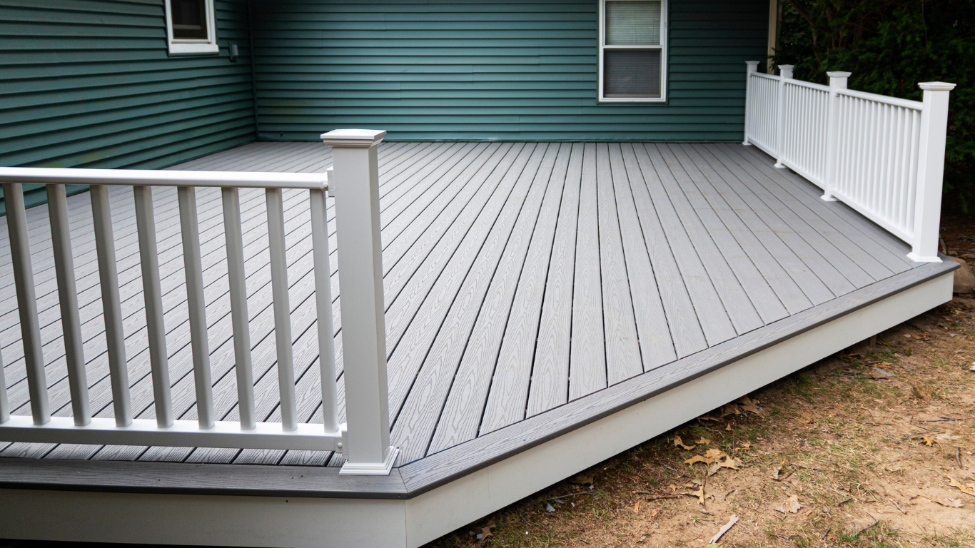 Gray composite deck with white railing, against a teal house exterior.