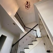 Interior view of a modern staircase with black wrought iron railing and a decorative light fixture.
