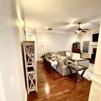 Open-concept living room with a couch, shelves, and hardwood floors.