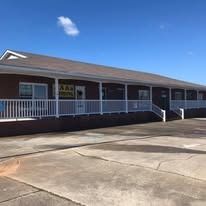 A one-story brick building with a white railing and blue sky.