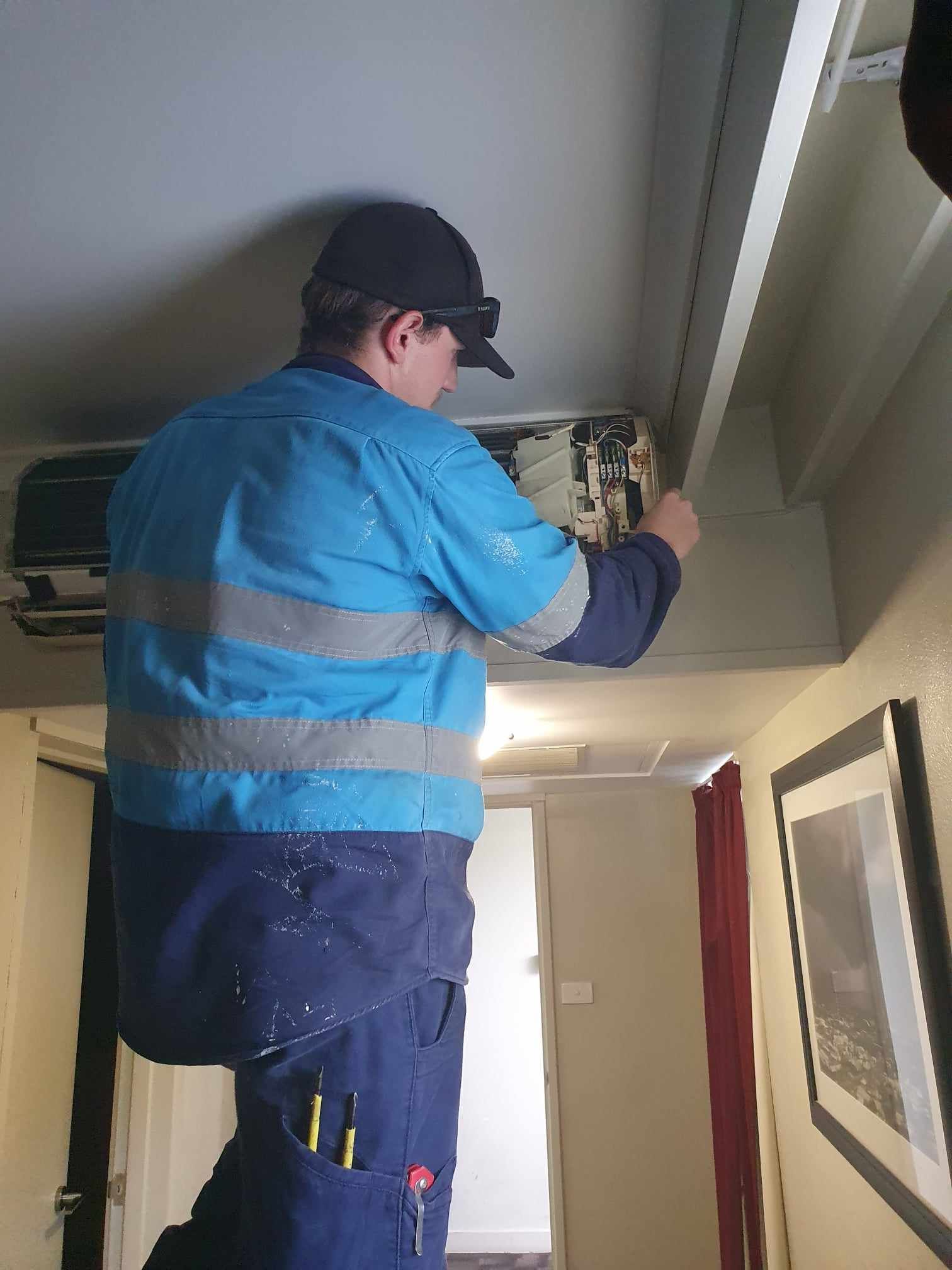 A man is working on a ceiling fan in a room.
