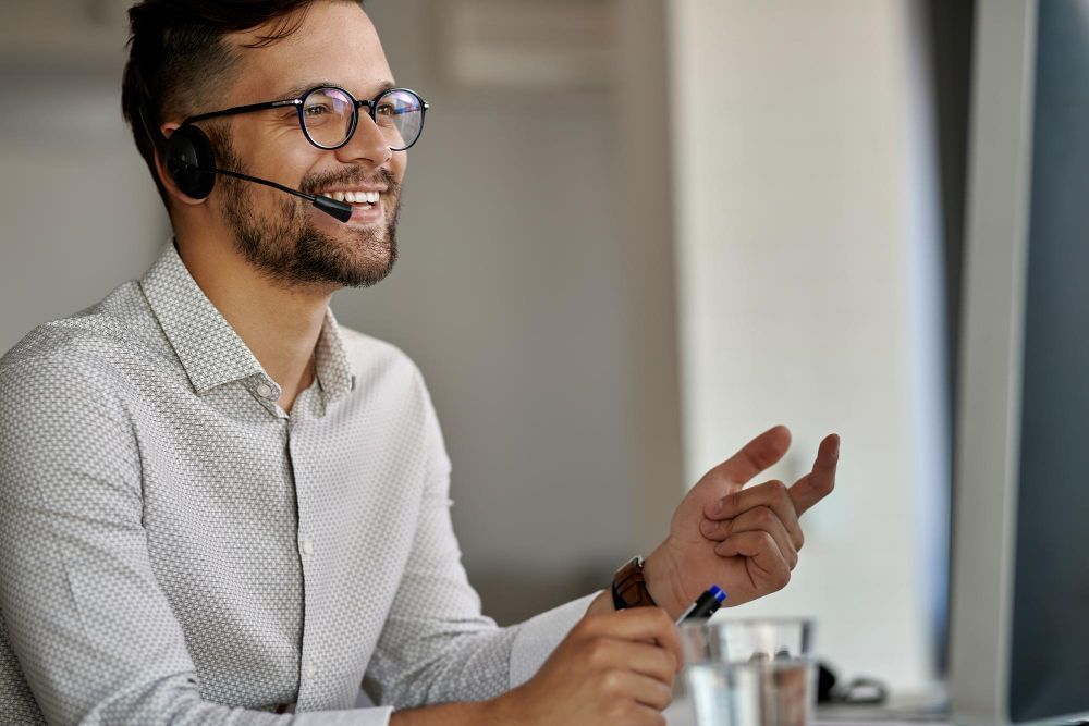A man wearing a headset is sitting in front of a computer.
