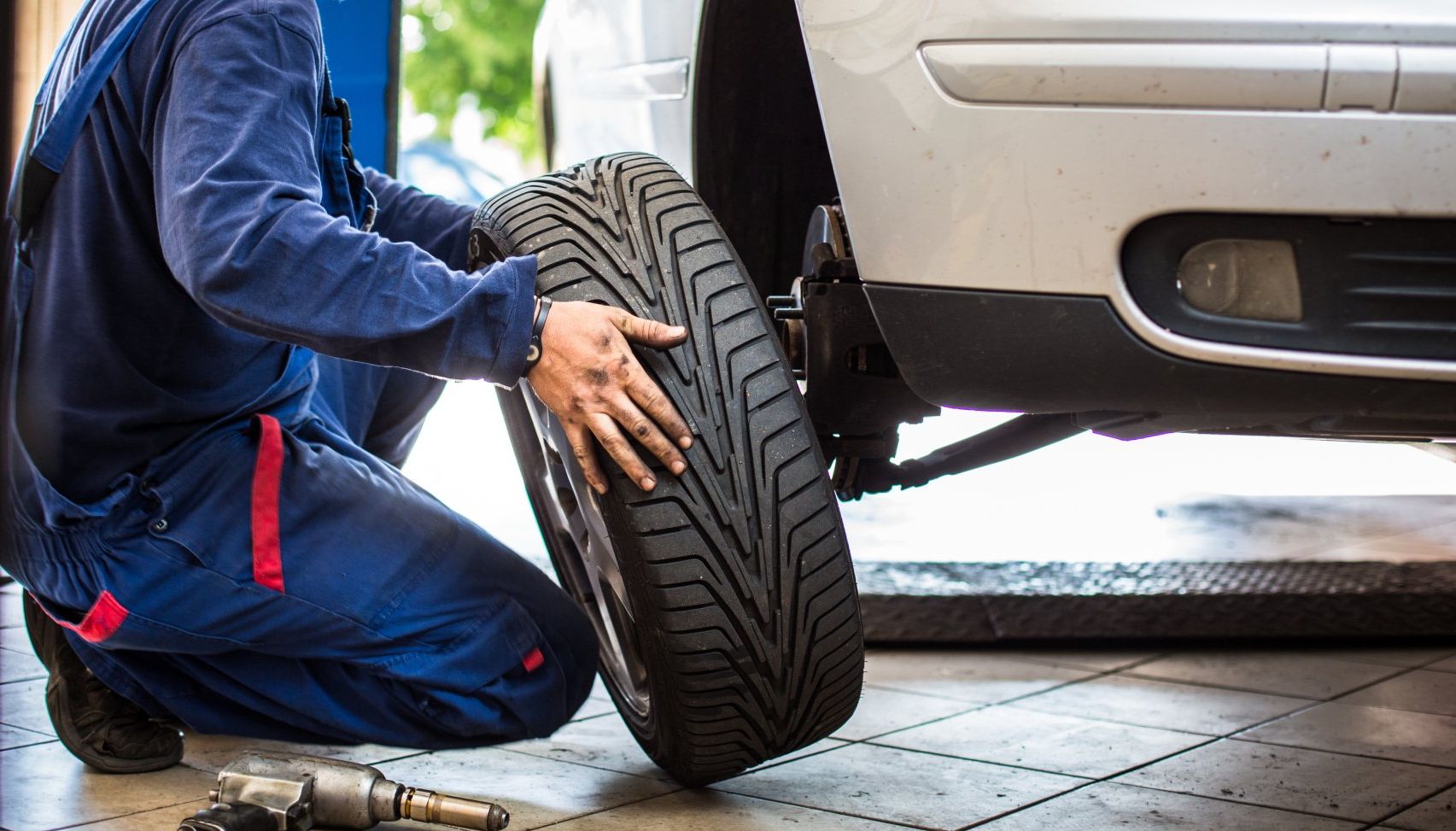 Un mécanicien s agenouille pour changer un pneu sur une voiture.