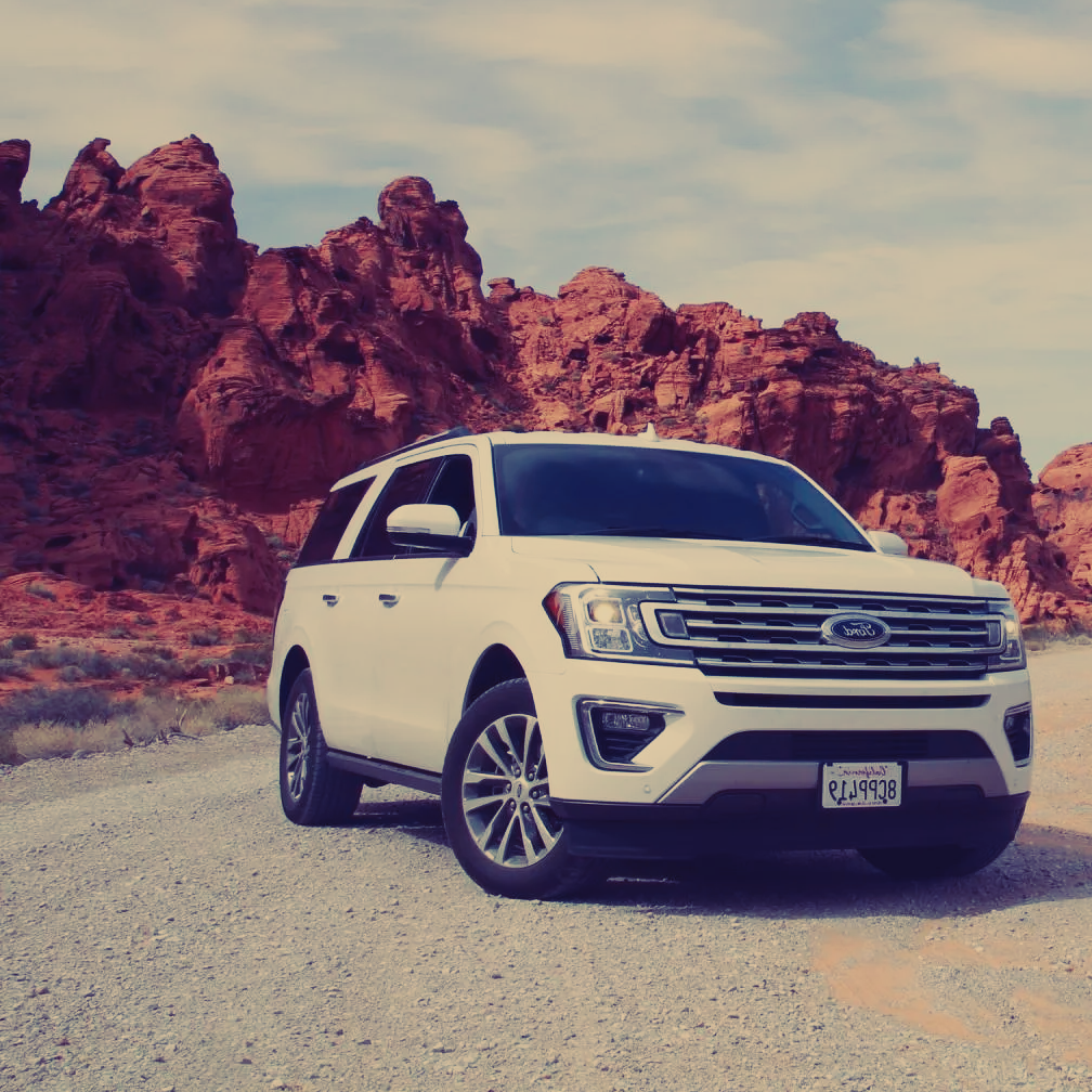 A white ford suv is parked on a dirt road