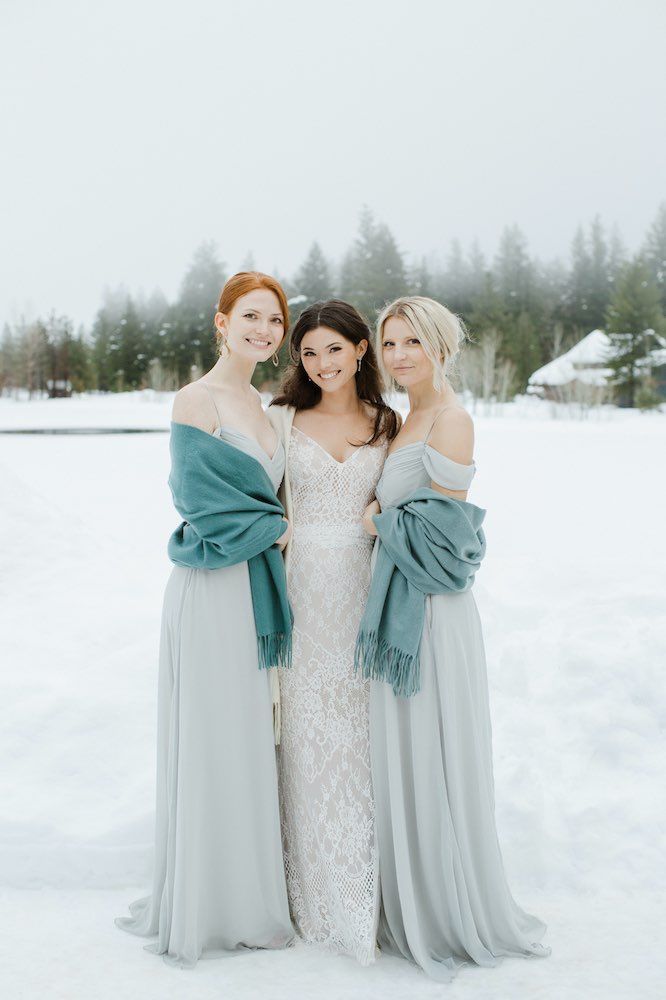 A bride and her bridesmaids are posing for a picture in the snow.
