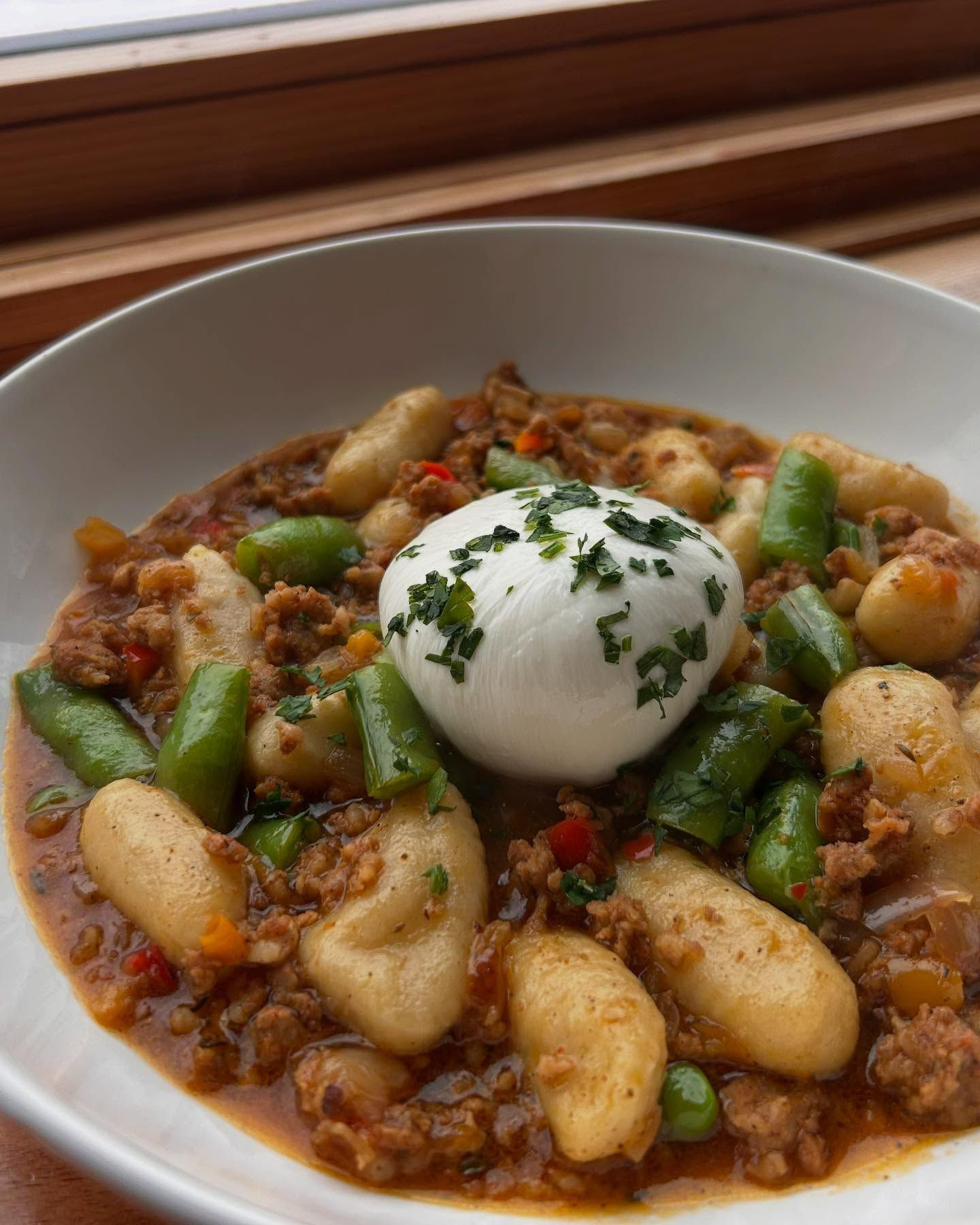 A bowl of food with gnocchi green beans and a hard boiled egg on top