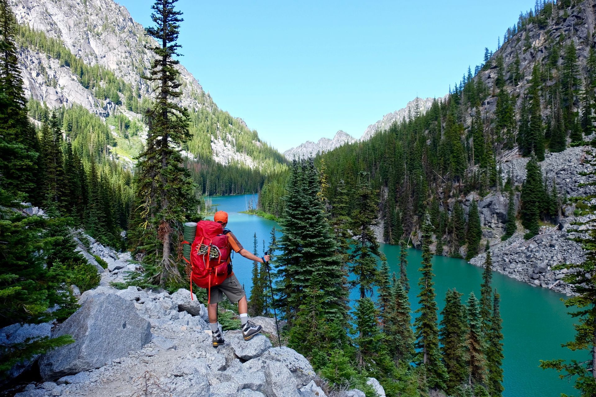 A woman is standing on top of a mountain with her arms outstretched.