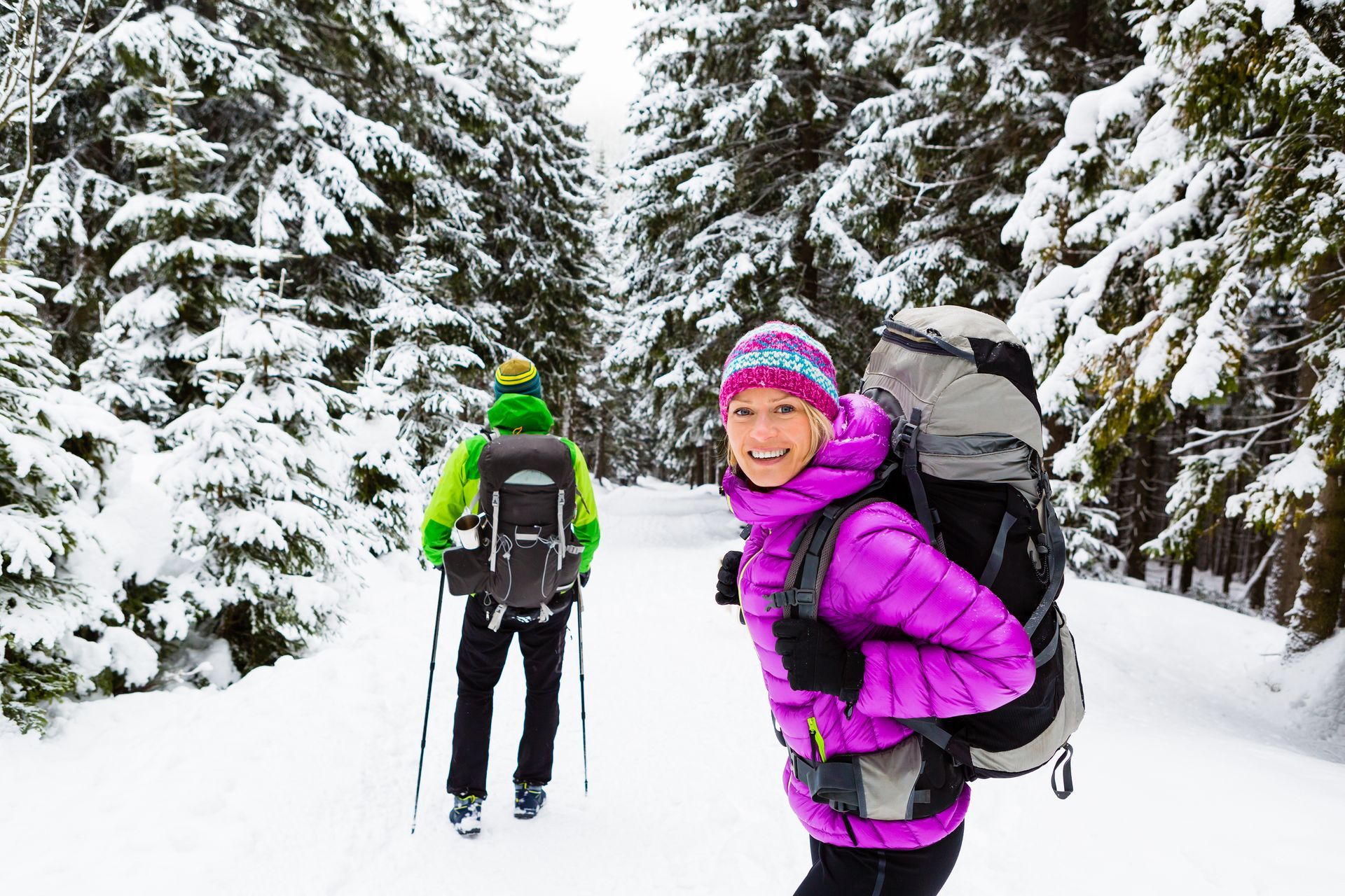 A man and a woman are hiking in the snow.