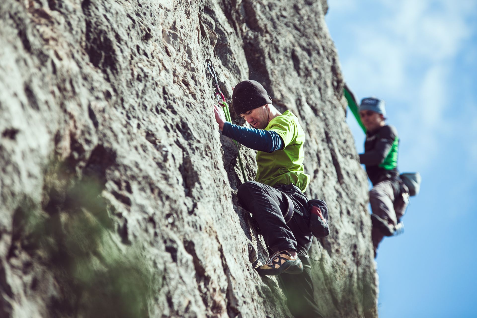 Two men are climbing up a rock wall.