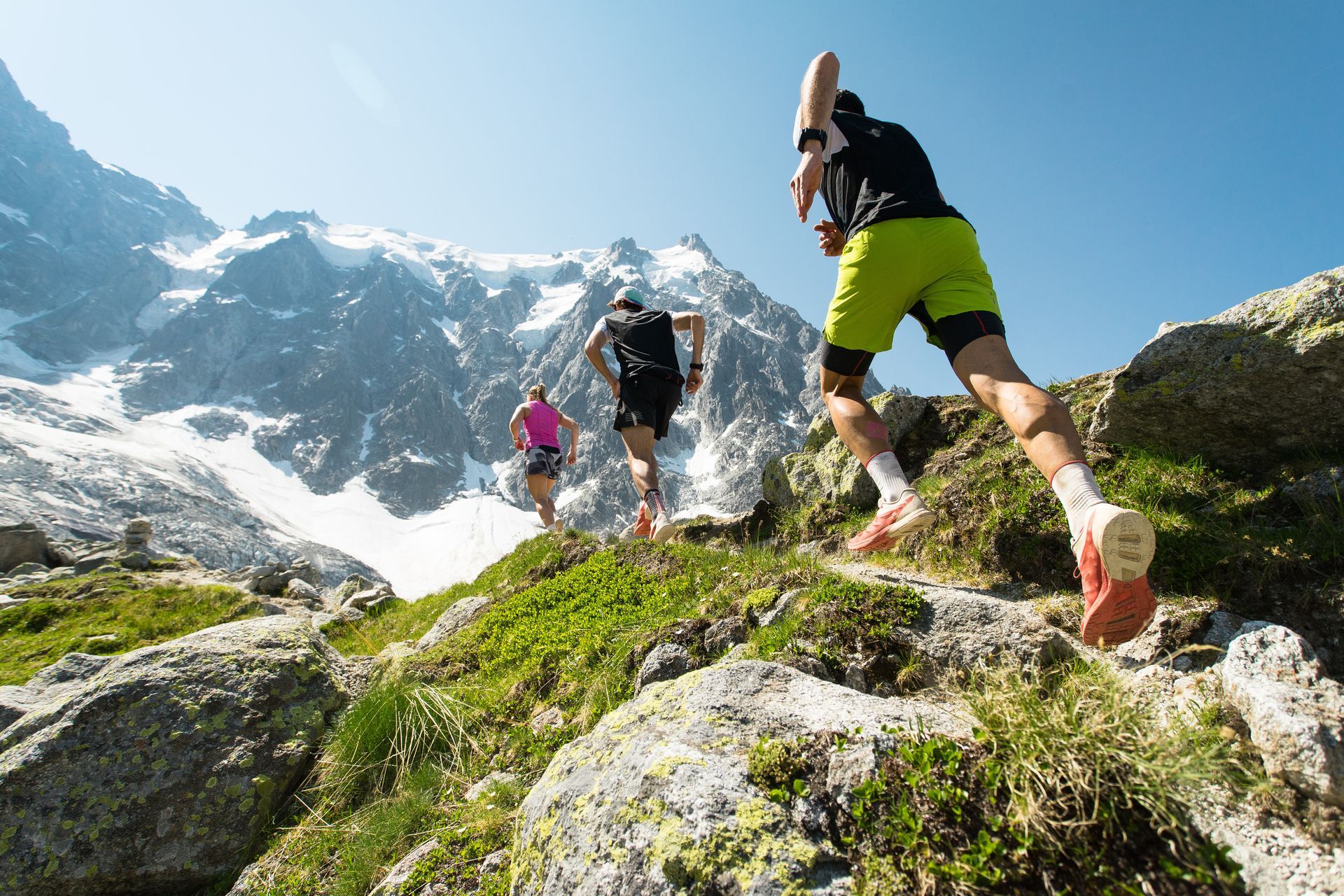 A group of people are running on a trail in the mountains.