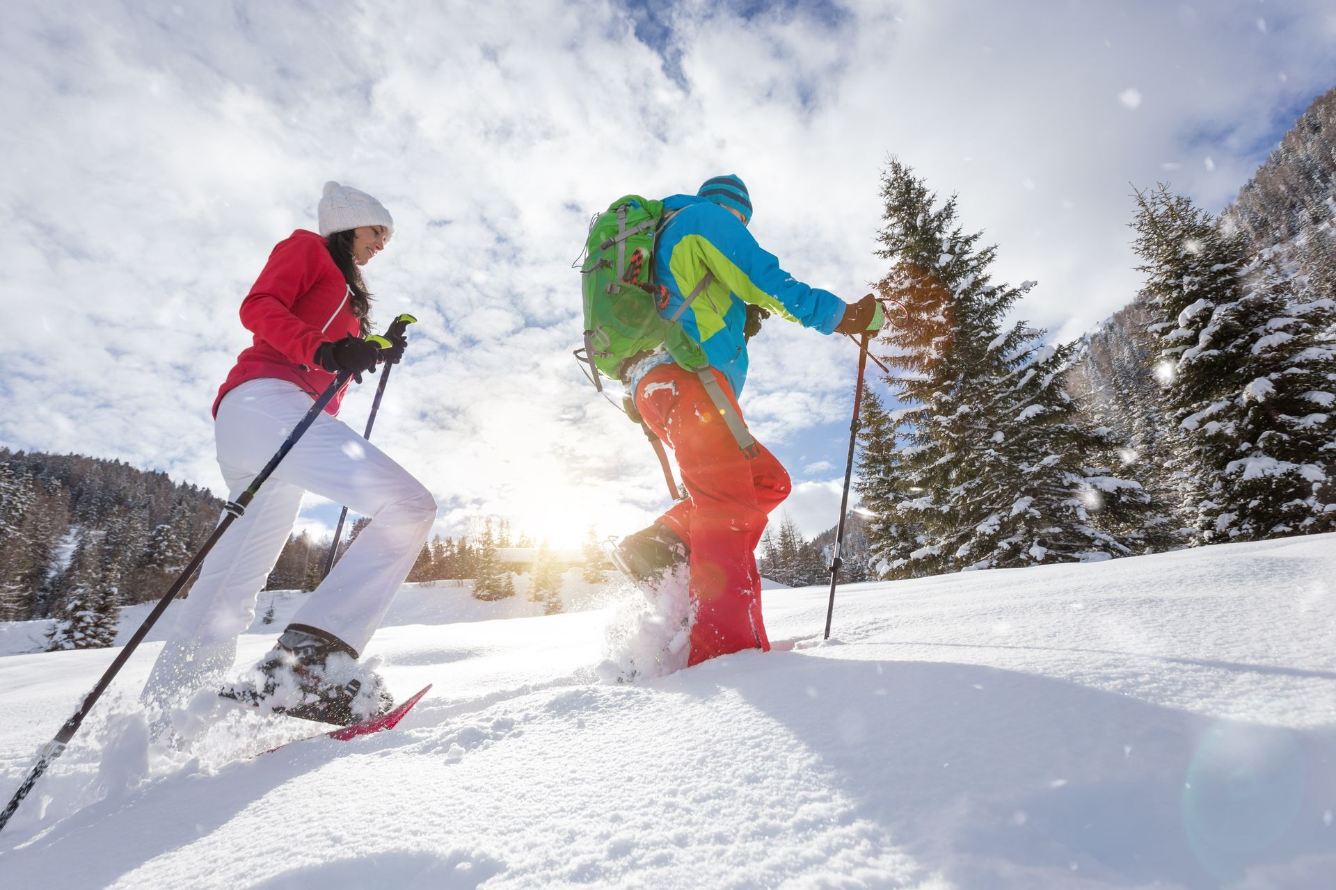 A man and a woman are snowshoeing in the snow.