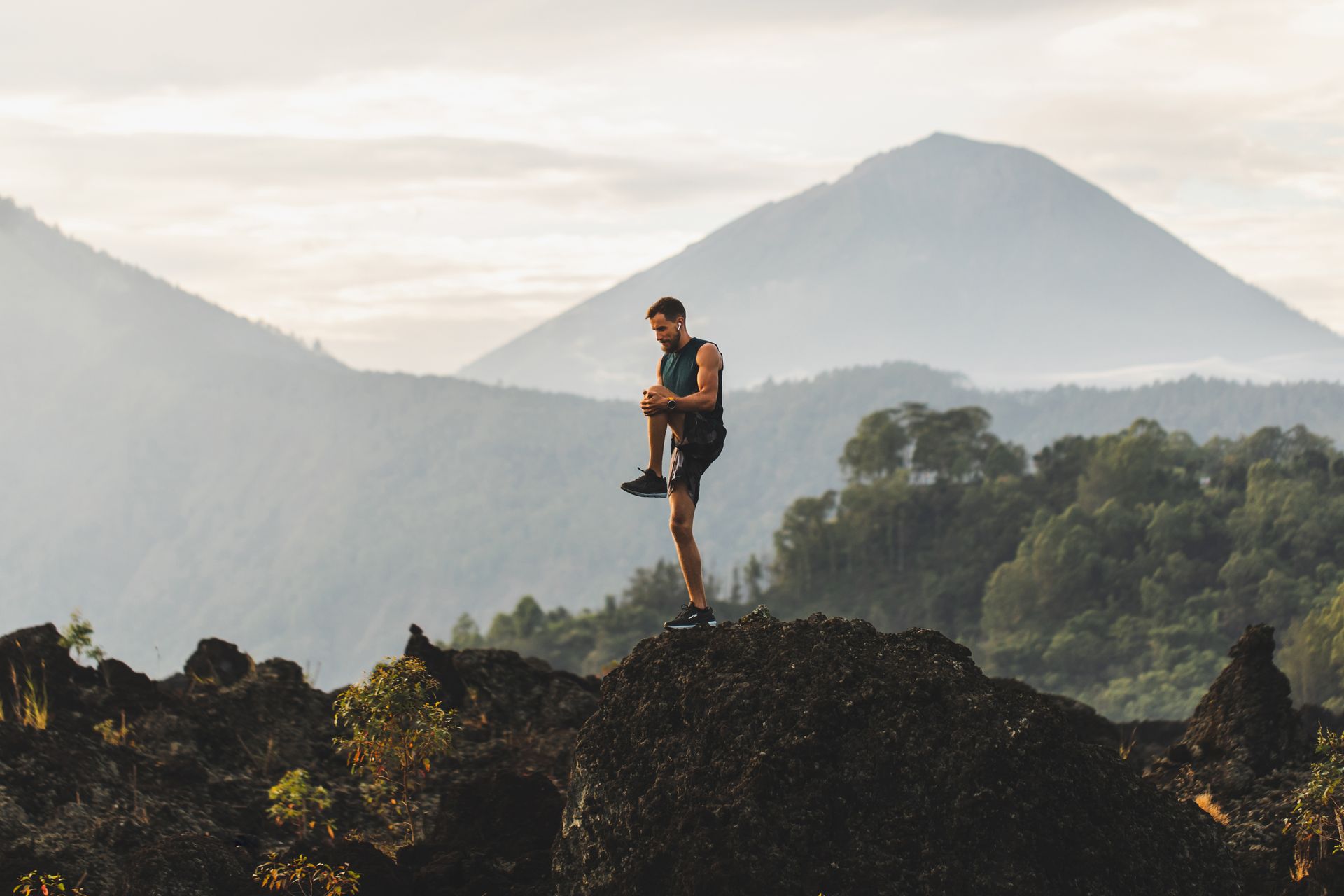 A man is standing on top of a rocky hill.