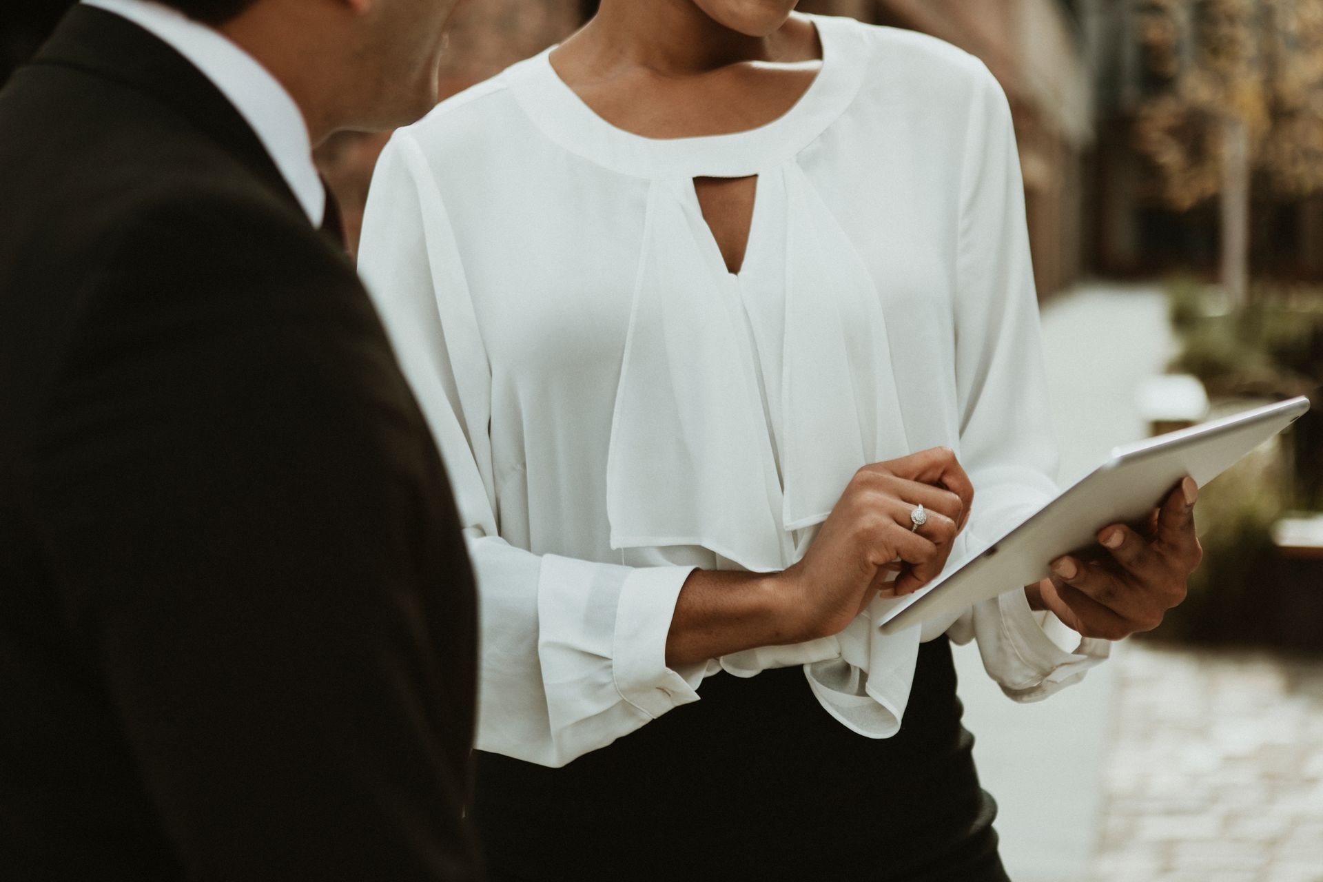 A man and a woman are standing next to each other looking at a tablet.