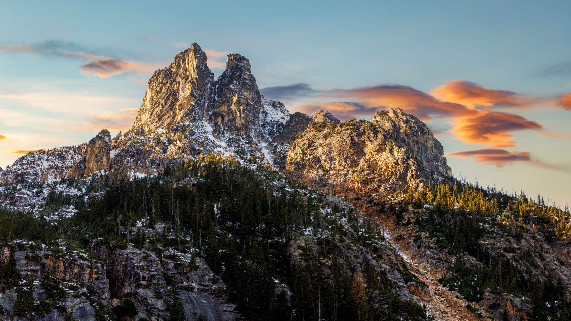 A mountain covered in snow and trees with a cloudy sky in the background.