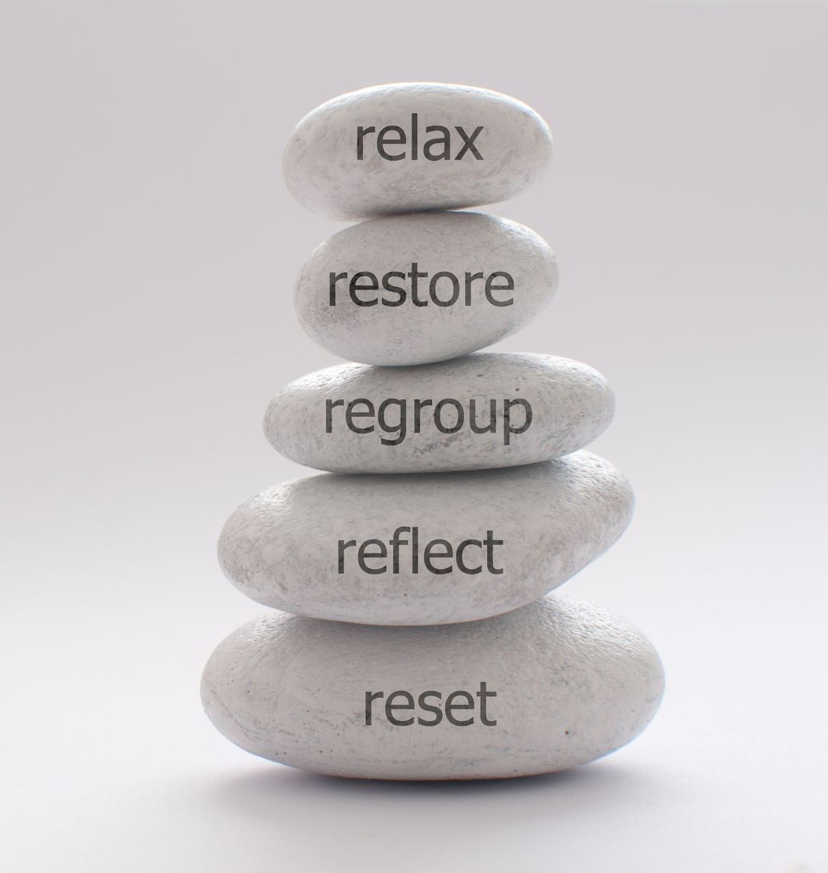 A stack of rocks with the words relax restore regroup reflect reset written on them