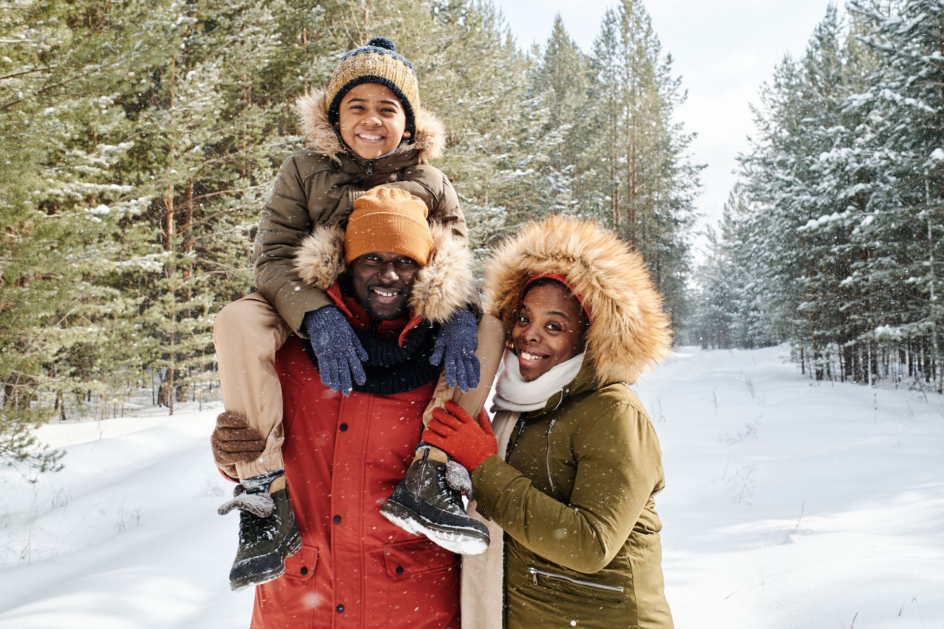 A man is carrying a child on his shoulders in the snow.