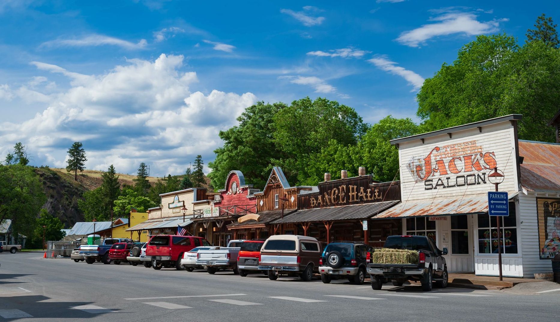 A row of cars are parked in front of a saloon.