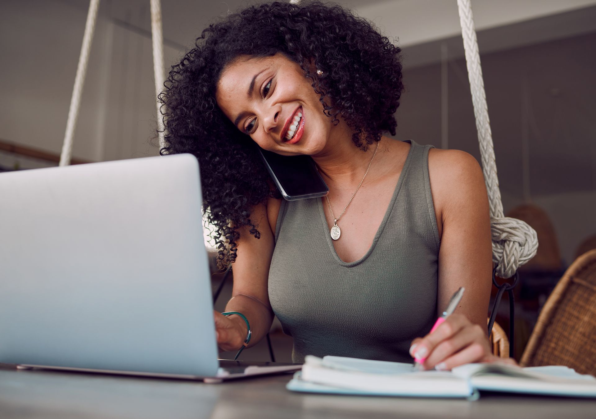 A woman sitting at the table with a laptop and a notebook.