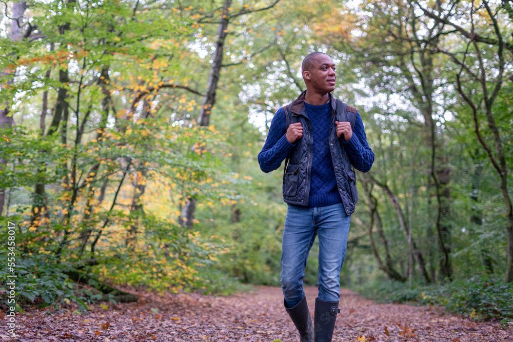 A man is walking down a path in the woods.