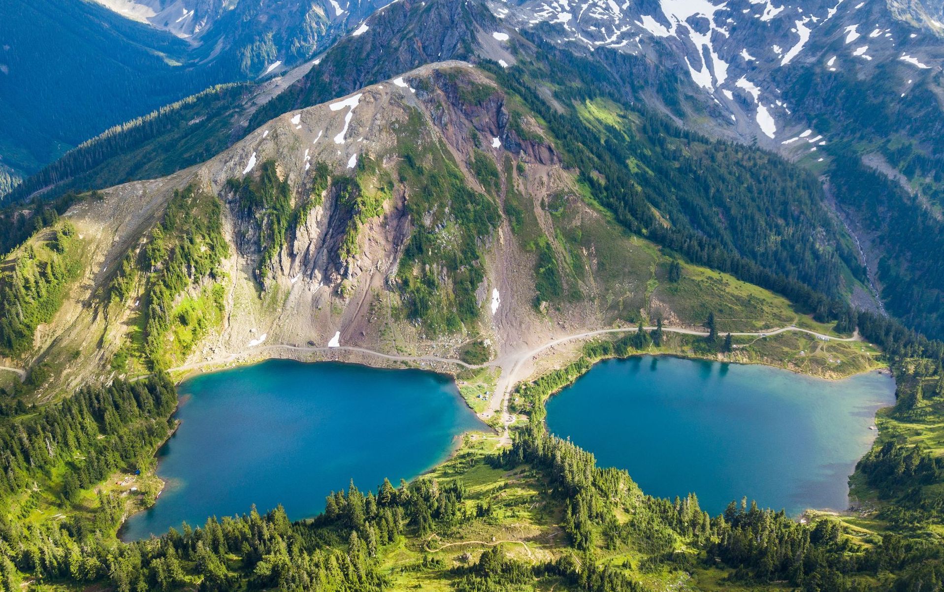 There are two lakes in the middle of a mountain surrounded by trees.