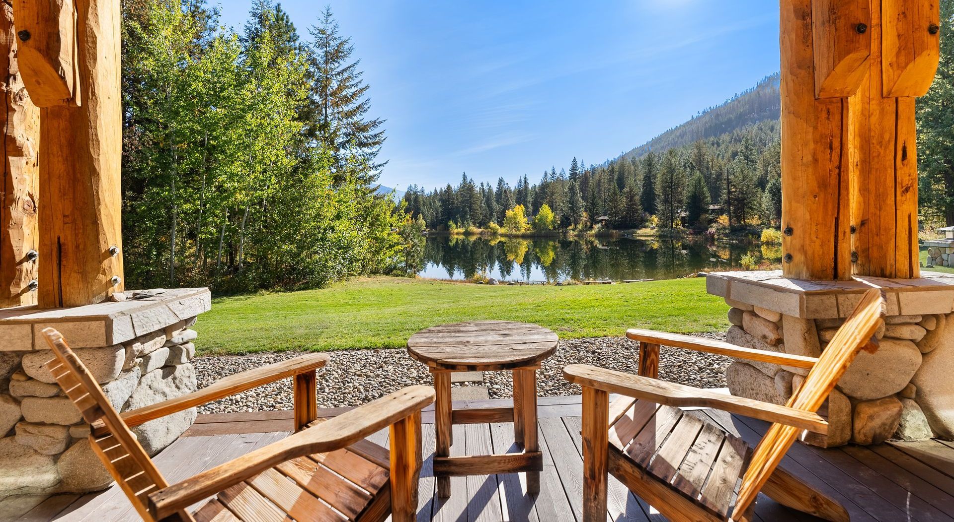 Two wooden chairs are sitting on a porch overlooking a lake.