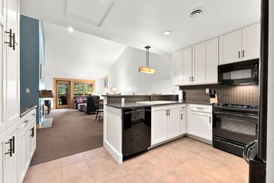 A kitchen with white cabinets , black appliances , and a stove.