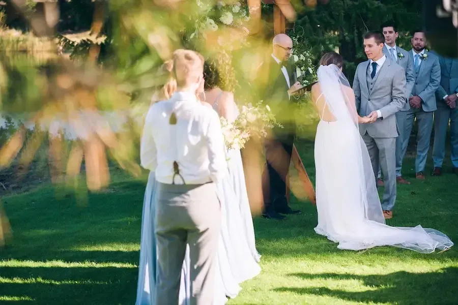 A bride and groom are holding hands during their wedding ceremony.