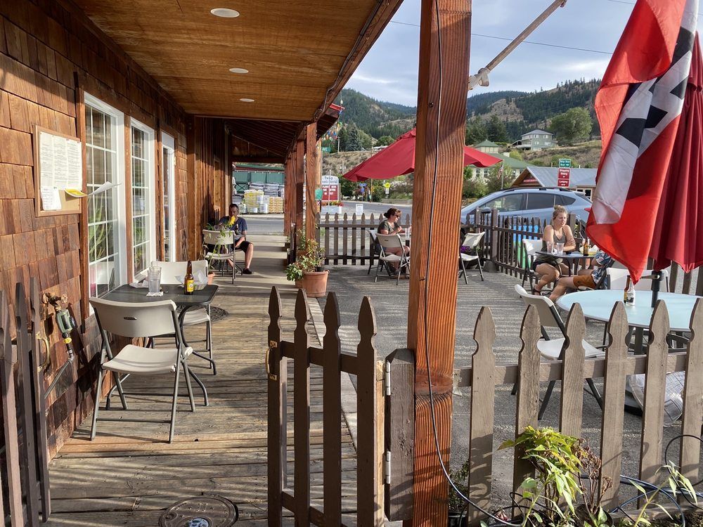 A wooden porch with tables and chairs and an umbrella.