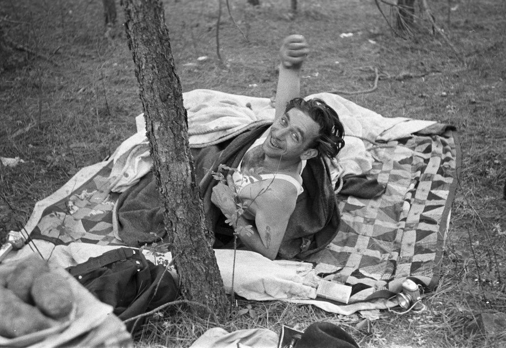 black and white photo of a man on a blanket near a tree